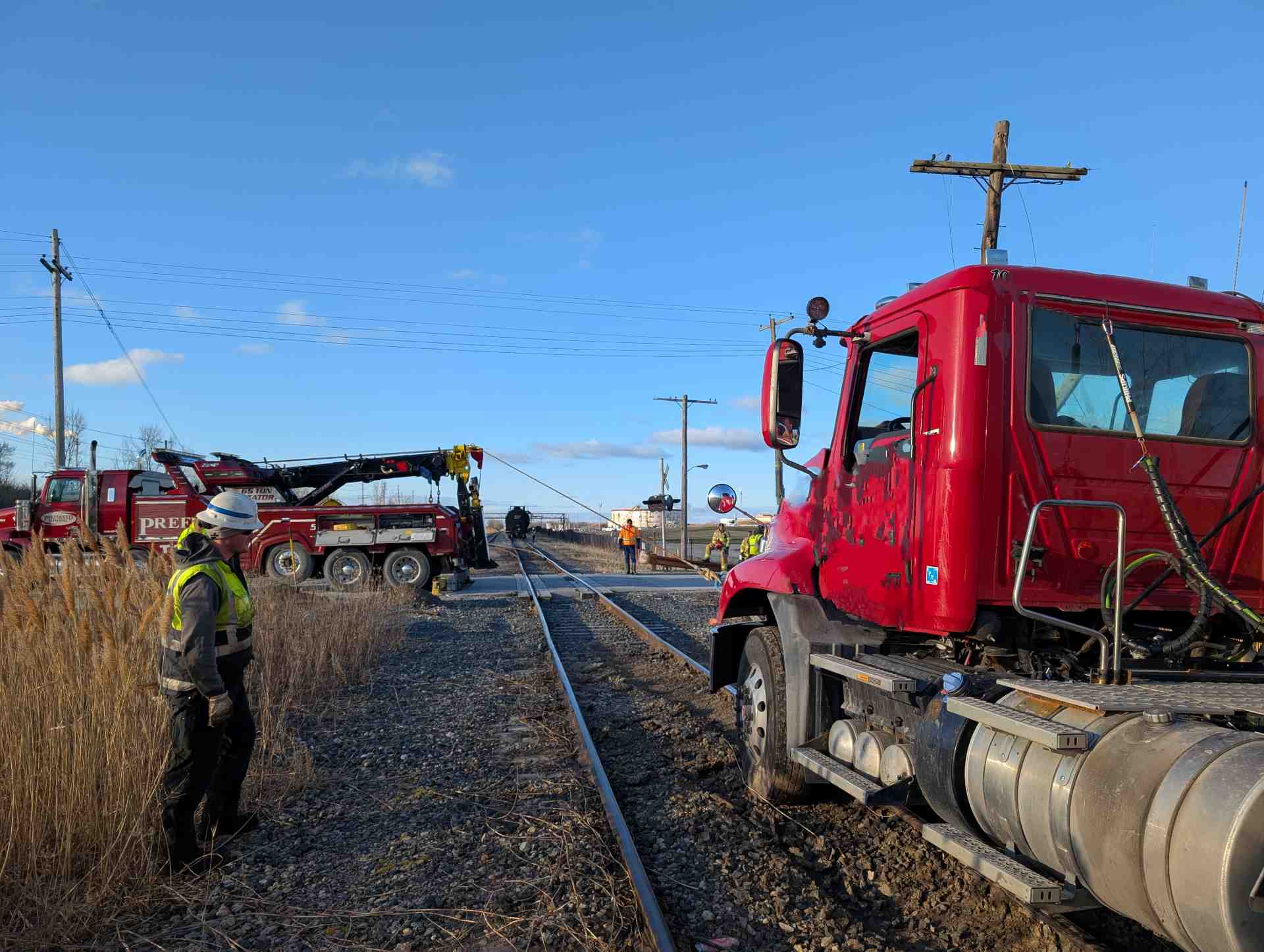 Image of a tractor trailer stuck on the train tracks, with a tow truck operator assessing the situation. (Photo courtesy Collin Vandenheuvel)